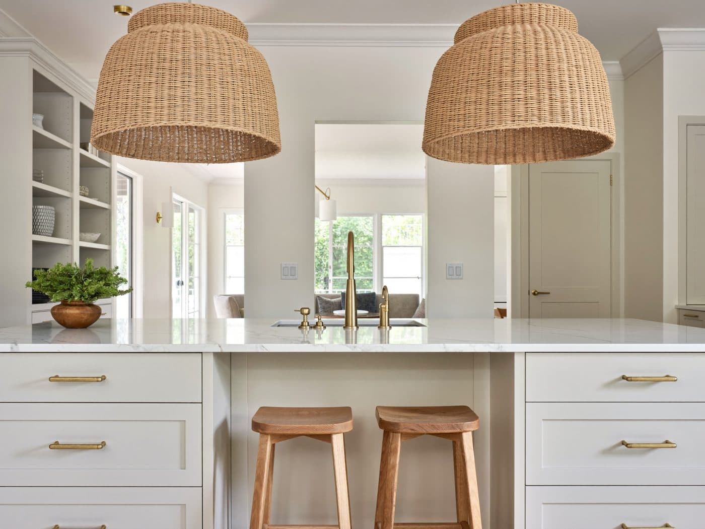 Bright remodeled kitchen with a white island, wood stools and woven pendant lights