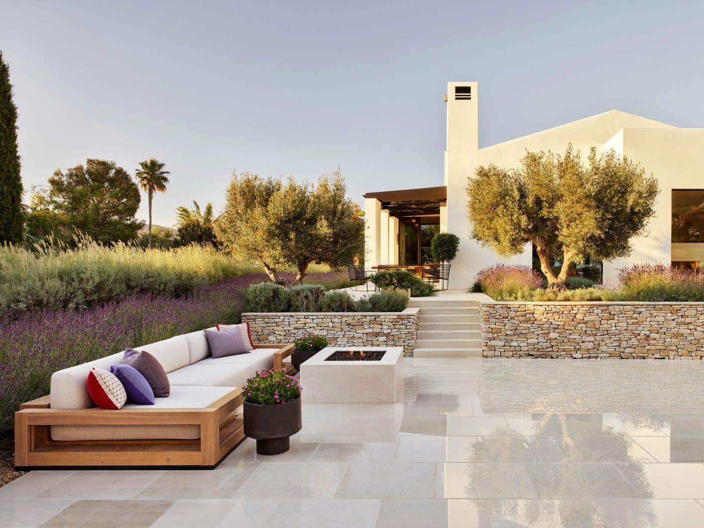 Stone patio with outdoor seating, olive trees and drought-tolerant planting